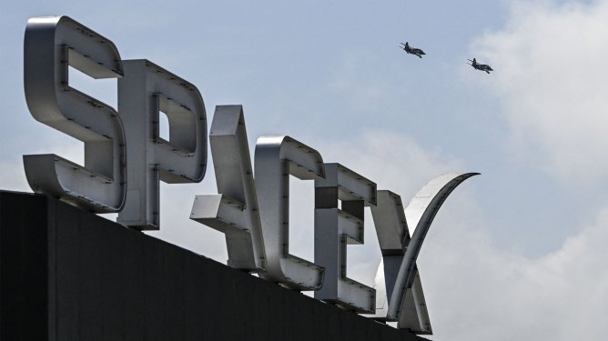 US billionaire businessman and pilot Jared Isaacman flies in formation aboard a fighter jet over the SpaceX sign, close to the Starship spacecraft, before his third test flight from Starbase in Boca Chica, Texas, on March 13, 2024.