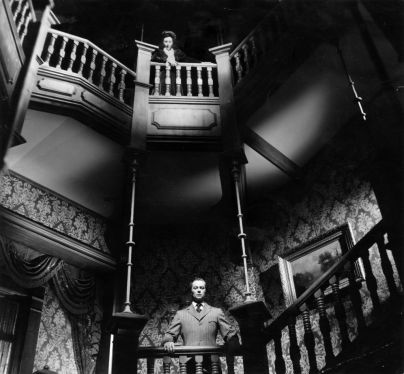 Actress Agnes Moorehead stands on a landing, watching actor Tim Holt, on the floor below in a scene from Orson Welles' masterful RKO production 'The Magnificent Ambersons'.