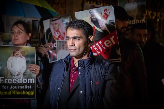 a photo of Ghanem al-Dosari, surrounded by protest signs.