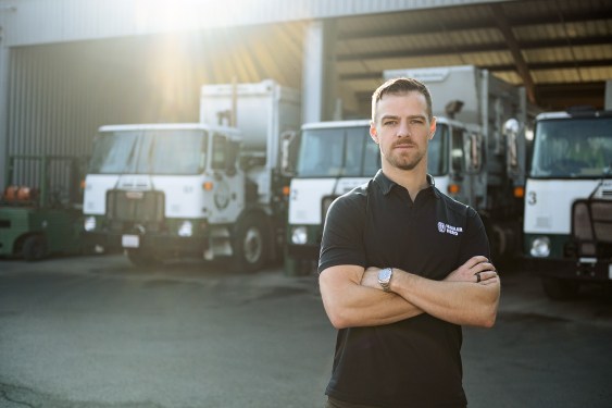 Image of Mark Hoadley, Hauler Hero co-founder and CEO, in front of garbage trucks.