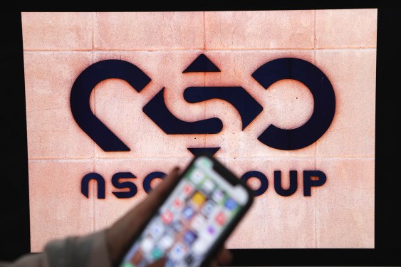 A photographic illustration shows a mobile phone near the NSO Group company logo on February 9, 2022 in the Israeli city of Netanya.